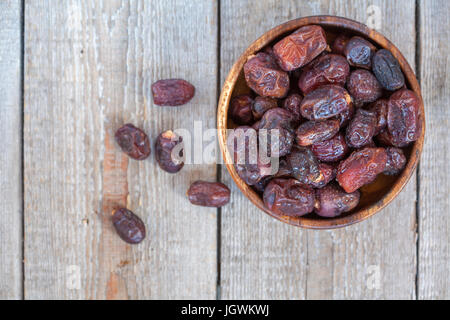 Fresh dates in wooden bowl. Love for a healthy vegan food concept. Stock Photo