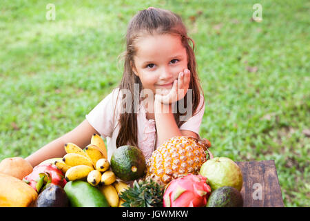 Exotic fruit on wooden table. Summer background with Laughing happy girl Stock Photo