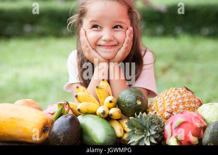 Exotic fruit on wooden table. Summer background with Laughing happy girl Stock Photo