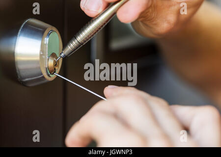 closeup of locksmith hands using pick tools to open locked door Stock Photo