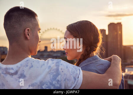 Young couple in front of skyline at sunset roof party in London, UK Stock Photo