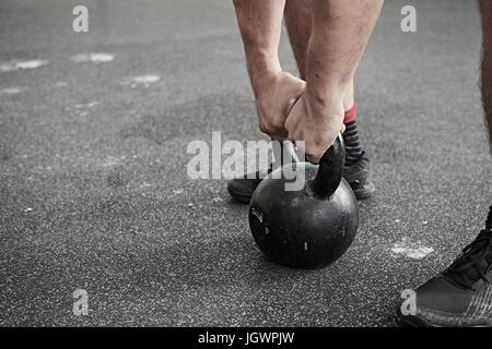 Man lifting kettlebell in cross training gym Stock Photo
