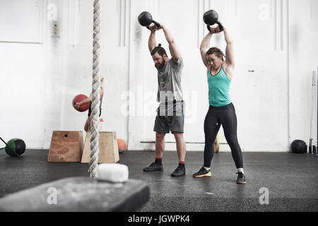 Couple working out with kettlebells in cross training gym Stock Photo