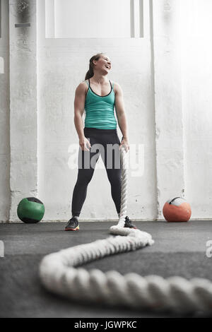 Woman holding battle rope in cross training gym Stock Photo