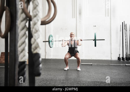 Woman lifting barbell in cross training gym Stock Photo