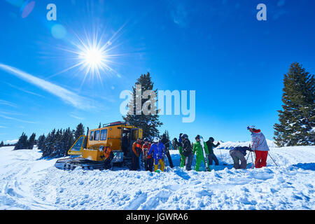 Male and female skiers on ski slope by snow coach, Aspen, Colorado, USA Stock Photo