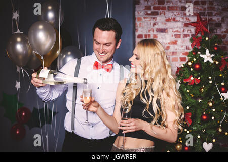 Man and woman at party, man pouring champagne into woman's glass Stock Photo