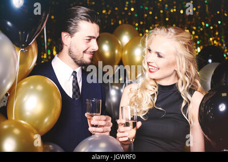 Young man and woman at party, holding champagne glasses, smiling Stock Photo