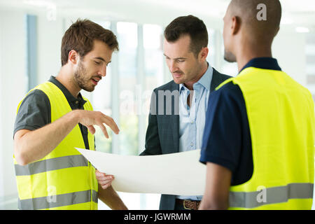Construction workers and businessman, looking at plans Stock Photo