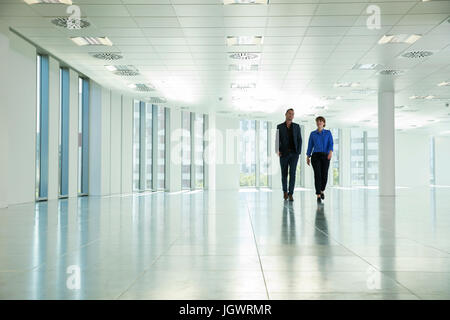 Businessman and woman walking through empty office space Stock Photo