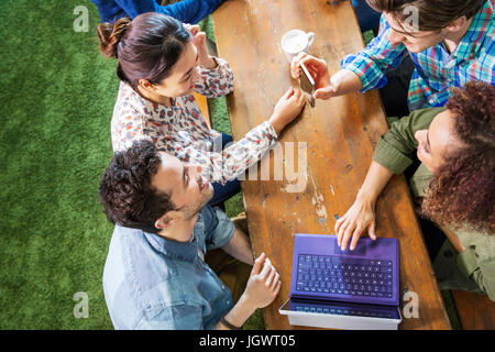 Overhead view of digital designers at office table looking at smartphone Stock Photo