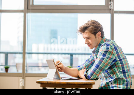 Young male digital designer at office table using laptop Stock Photo