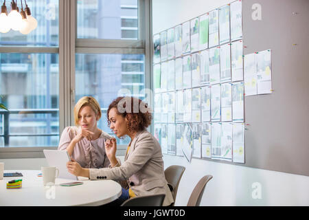 Two female digital designers looking at digital tablet at desk Stock Photo