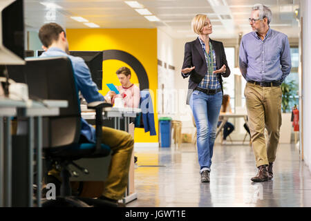 Female and male digital designers walking and talking in office Stock Photo