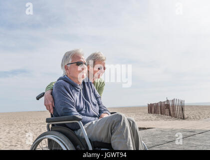 Senior man in wheelchair with wife at beach, Santa Monica, California, USA Stock Photo