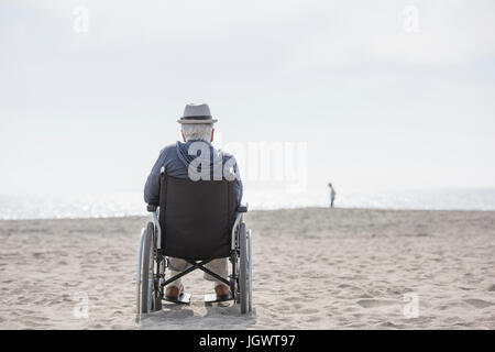 Rear view of senior man in wheelchair looking out from beach, Santa Monica, California, USA Stock Photo