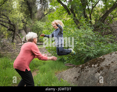 Grandson jumping off rock into grandmother's arms, Sequoia National Park, California, US Stock Photo