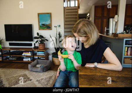 Boy sitting on mother's lap laughing Stock Photo