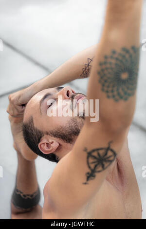 Man practicing yoga, standing on one leg touching toes Stock Photo
