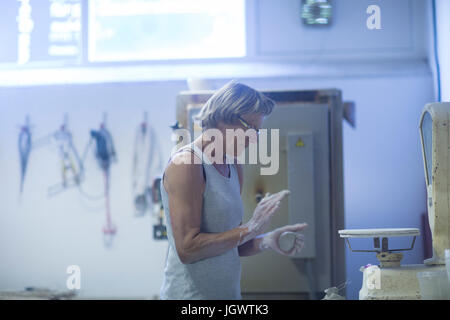 Senior woman in pottery workshop, weighing clay for pottery project Stock Photo