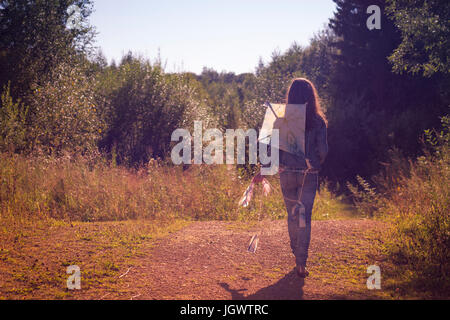 Rear view of teenage girl walking with kite along dirt track Stock Photo