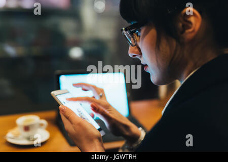 Businesswoman using mobile phone and laptop in cafe Stock Photo