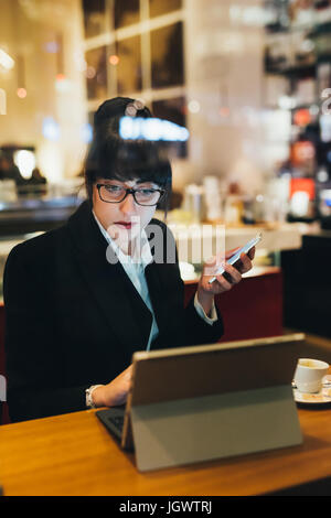 Businesswoman using mobile phone and digital tablet in cafe Stock Photo
