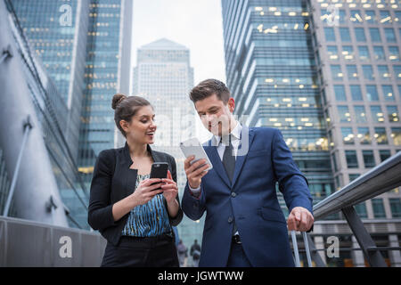 Businessman and businesswoman using mobile phone, Canary Wharf, London, UK Stock Photo