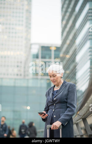 Businesswoman using mobile phone, Canary Wharf, London, UK Stock Photo