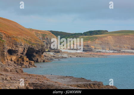 A distant beach with many bathers and sun seekers relaxing and playing on a sandy beach on a warm July day with the tide out. Stock Photo