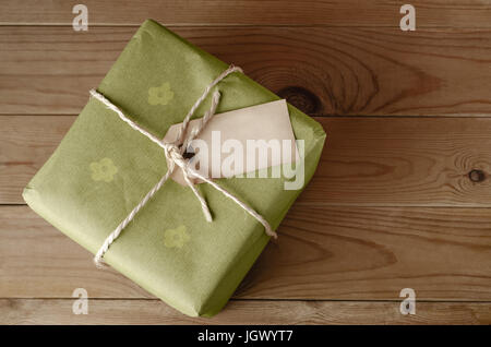 Overhead shot of a parcel, tied with string and wrapped in green floral wrapping paper.  Blank label faces upwards to provide copy space.  Set on an o Stock Photo