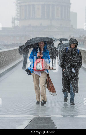 London, UK. 11th July, 2017. Stormy weather brings rain to London and catches tourists out in shorts and t-shirts, while the lucky few take shelter under umbrellas as the y cross the Millennium Bridge from St pauls cathedral. London 11 July 2017. Credit: Guy Bell/Alamy Live News Stock Photo