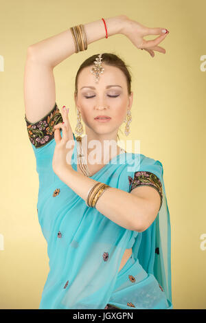 beautiful woman in Indian dress dancing on yellow background, toned image Stock Photo