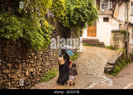 ISTANBUL, TURKEY - May 6, 2017: Unknown woman with umbrella and children walking on streets of balat area.Street view in historical Balat district. Ba Stock Photo
