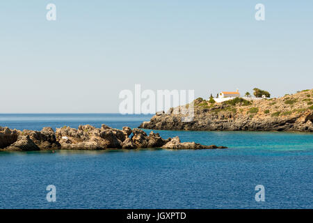 A sunbather finds solitude on a small islands of the south coast of western Crete, Greece, at Loutro. A solitary umbrella provides shade. Stock Photo