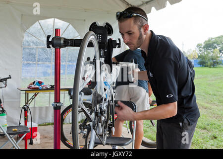 Bicycle mechanic fixing wheel with bicycle mounted on bike mount - USA Stock Photo