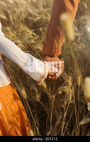 Cropped view of couple holding hands in wheat field Stock Photo