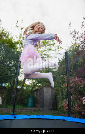 Girl bouncing on trampoline wearing tutu Stock Photo