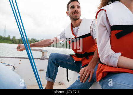 Man and woman on sailing boat, man steering boat Stock Photo