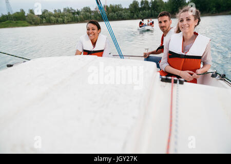 Three friends on sailing boat, on lake Stock Photo