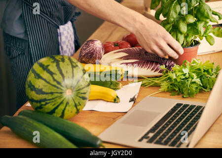Cropped view of chef with variety of fruit, vegetables and herbs Stock Photo