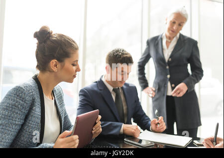 Businessman and women making notes in boardroom meeting Stock Photo