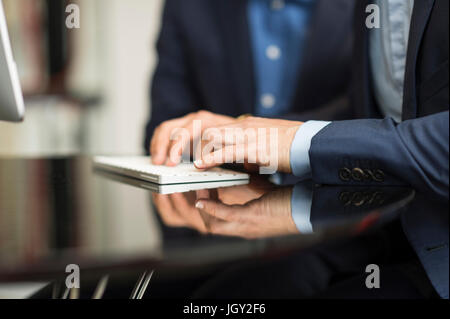 Detail of businessman's hands typing on desktop computer keyboard Stock Photo