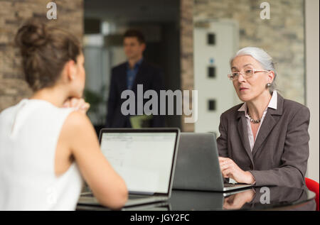 Mature businesswoman and female colleague having discussion over office desk Stock Photo