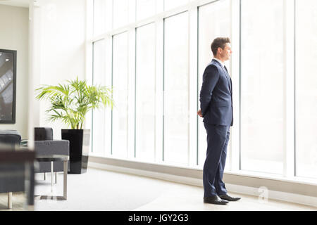Confident businessman looking through office window Stock Photo