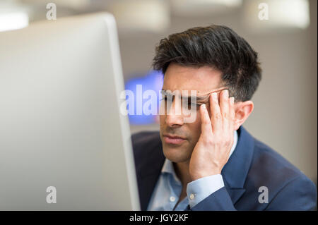 Confused businessman looking at computer in office Stock Photo