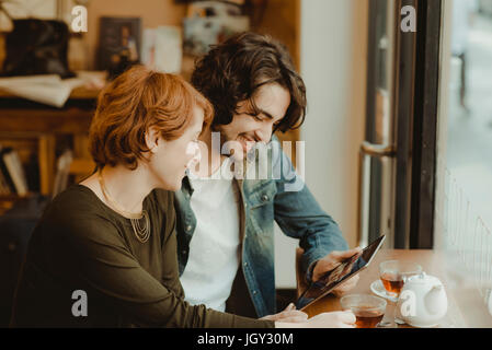 Young couple sitting in cafe, looking at digital tablet Stock Photo