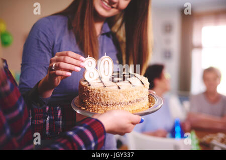 Daughter preparing birthday cake for mother at birthday party Stock Photo