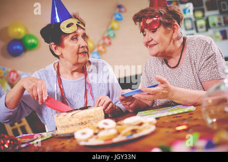 Senior women serving birthday cake at party Stock Photo