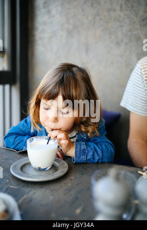 Girl sipping milk in cafe Stock Photo